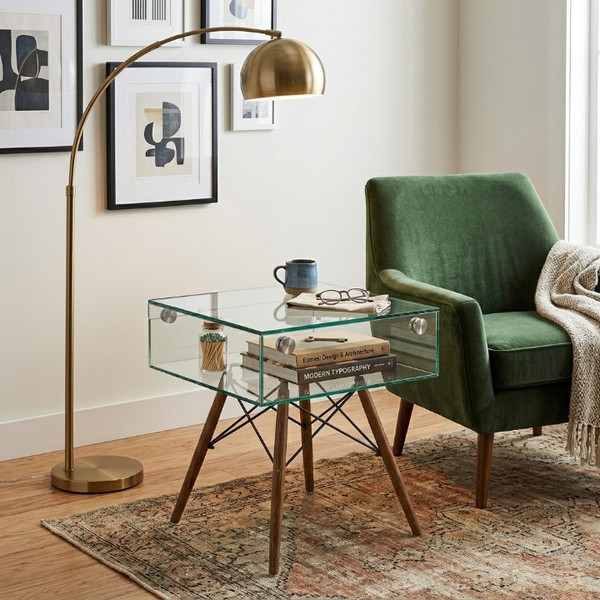 Shelf Bent Clear Glass Side Table Set with books and a mug next to a green chair and floor lamp in a stylish living room.