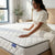 Woman sitting on the 1.5M Comfort Sleep Mattress, showcasing comfort and design in a modern bedroom.