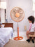 12 Inch Colourful Pedestal Fan standing in a bedroom next to a child sitting on a stool.
