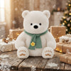 23cm Plush Polar Bear dressed with a green scarf, sitting on a wooden table surrounded by snow and gifts.
