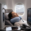 A traveler relaxing in an airplane seat with a Velvet Neck Pillow, showcasing comfort during travel.
