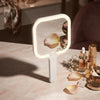Portable Square LED Makeup Mirror with built-in lighting on a vanity table, surrounded by beauty products.