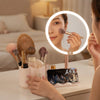 LED Makeup Mirror with Rotating Cosmetic Organizer featuring a user applying makeup and using a phone stand.