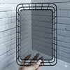 Metal Wire Grid Basket Organizer held against a white brick backdrop, showcasing its sturdy design and mesh texture.
