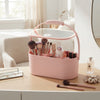 Portable Vanity Mirror Makeup Organizer Case with brushes and cosmetics in a light pink, modern design on a vanity table.