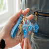 Blue Liquid Glitter Floating Charm Keychain attached to a backpack with keys for a playful accessory.