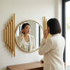 Woman in a white blazer admiring her reflection in a Luxury Oval Wall Mirror with decorative gold accents.