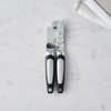 Heavy-Duty Polished Stainless Steel Manual Can Opener on a marble countertop with a dish towel.