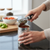 Person using a Heavy-Duty Polished Stainless Steel Manual Can Opener on a can in a kitchen.
