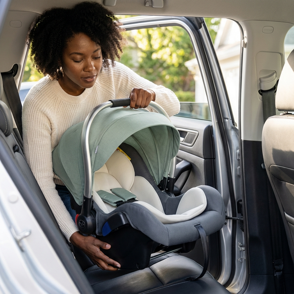 Parent installing the Baby Basket-Style Car Safety Seat in a vehicle for safe travels with their newborn.