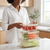 Person organizing fresh vegetables and tomatoes in the Deluxe 5-Piece Stackable Airtight Food Container Set.