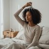 Woman using Head Massager Battery Version for relaxation while sitting on a bed in a cozy room.