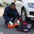 A man using a Portable 3 Ton Electric Jack Emergency Tool Set beside a vehicle for roadside assistance.