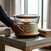 A hand adjusting the dial on the Multi-function BBQ Safety Switch Heater on a coffee table in a cozy living room.