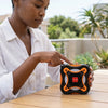 Woman using 1500W Flower Shape PTC Ceramic Fan Heater outdoors on a wooden table.