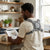 Man reading a newspaper while wearing a Spine Posture Corrector and Back Support in a home kitchen.