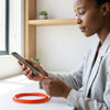 Woman using Transparent Fast Charging Data USB Cable to charge her smartphone on a desk.