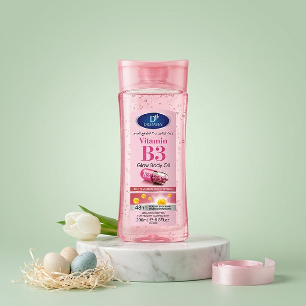 Vitamin B3 Vitamin E Body Oil Gel in a pink bottle on a marble surface with flowers and decorative eggs.