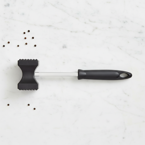 Meat hammer kitchen tenderiser tool with ergonomic handle on a marble countertop.