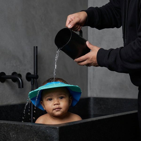 Baby Shower Cap worn by a baby during bath time, keeping water out of their eyes and providing a fun bathing experience.