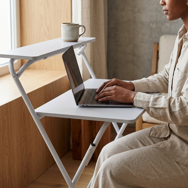 Person using a laptop on a Metal Legs Folding Computer Desk beside a window with a coffee cup.
