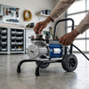 Electric High Pressure Airless Paint Sprayer with hose and wheels for easy transport in workshop.