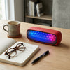 20W RGB Light Wireless Soundbox Speaker on a desk with coffee, glasses, and notebook.