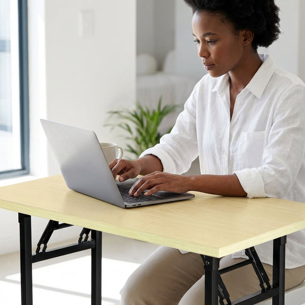 A woman using a laptop on a Single Computer Training Desk in a bright, organized workspace.