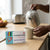Pouring hot water into a mug with Anti-Heart Failure Herbal Tea box on the table.