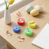 Single-Hole Bulk Plastic Standard Pencil Sharpener in red, blue, green, yellow on a desk with shavings and decorative eggs.