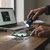 Person using a Mini Rechargeable LED Torch to illuminate a circuit board on a wooden table.
