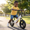Childrens 12-Inch Balance Bike being used by a smiling child in a park during sunny weather.