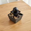 Indoor Tabletop Water Fountain Decor with stones on a wooden table, adding a peaceful ambiance to any space.