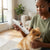 Person using USB Rechargeable Professional Pet Grooming Trimmer on a small dog in a cozy indoor setting.