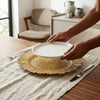 Person placing a plate on a 13-Inch Eco-Friendly Wedding Charger Plate for an elegant table setting.