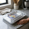 3-Piece Aluminum Nesting Oven Tray Set placed on a kitchen counter with a decorative label on the top.