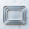 3-Piece Aluminum Nesting Oven Tray Set displayed on a marble surface, showcasing space-saving design.