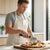 Man using Eco-Friendly Kitchen Pizza Cutter on freshly baked pizza in a modern kitchen.