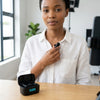Woman adjusting 2.4G Wireless Cardioid Lavalier Microphone for clear audio in a modern workspace.