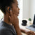User adjusting the X27 Air Conduction True Wireless Earbuds while working on a laptop.