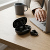 X58 TWS Wireless Ear Clip Sports Headphones in charging case on a wooden table with a laptop and coffee cup.