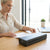 Woman using a Portable Wireless Thermal Printer on a wooden table with documents and a laptop.