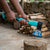 Person using a 600g Ergonomic Camping Hatchet to chop wood, showcasing its fiberglass handle and effective blade design.