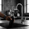 Person filling a black water bottle using a stylish 720 Degree Rotating Anti-Splash Faucet Aerator in a modern kitchen.
