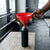 Person using a 250mm Large Multipurpose Food Grade Plastic Funnel to pour liquid into a black bottle in a gym setting.