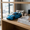 Die-Cast Racing Car Toy displayed on a wooden shelf with magazines in a modern living room.