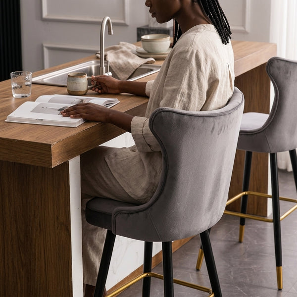 Modern Upholstered Bar Stool with Backrest in a stylish kitchen setting, featuring a woman enjoying a drink and reading.