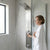 Woman enjoying a shower with the Stainless Steel Rainfall Waterfall Shower Panel in a modern bathroom.