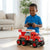 A child in a blue shirt playing with a remote-controlled Friction Powered Simulation Fire Truck Toy in a cozy room.
