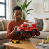 A woman playing with a Friction Powered Simulation Fire Truck Toy in a cozy living room.